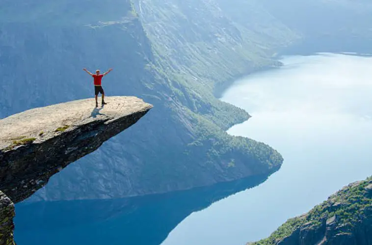 Pose for an expressive photo on Trolltunga peak highest hiking point in Norway,outstanding scenery in Norway, famous fjords in Norway, most adventurous thing to do in Norway, popular adventurous activity to do in Norway in winters